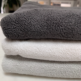 Close up of folded 900GSM cotton mats in charcoal, white and stone