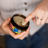 Image of woman removing natural deodorant from tub with her finger