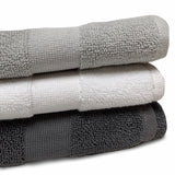 close up of folded organic cotton bath mats in stone, white and charcoal, featuring the dense 900GSM cotton