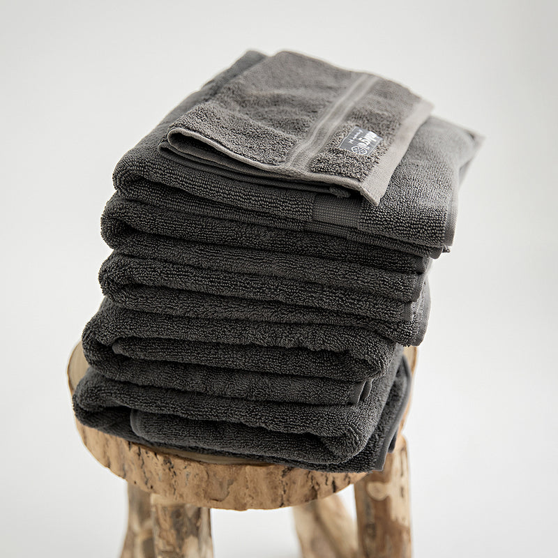 stack of charcoal towels in 7 piece set on a raw edge wooden stool with a pale background