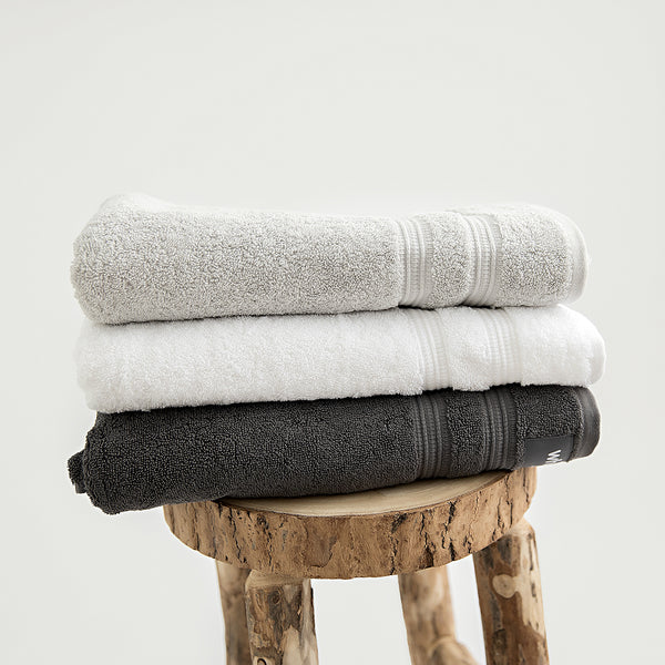 Organic bath towels in 700GSM GOTS cotton. Pictured in stone, white and charcoal.