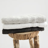 Set of 3 hand towels folded on stool. Stone, white and charcoal