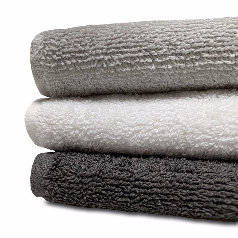 Close up of organic cotton bath towels in stone, white and charcoal showing density of cotton.